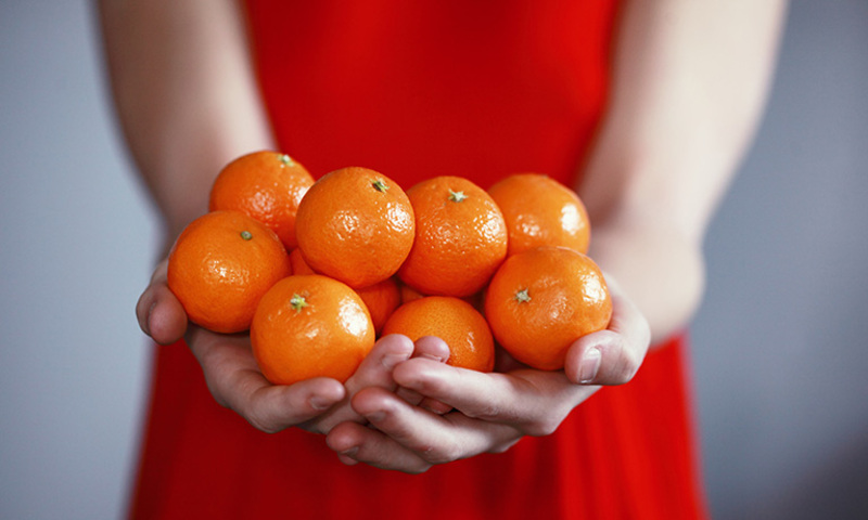 women in dress holding oranges