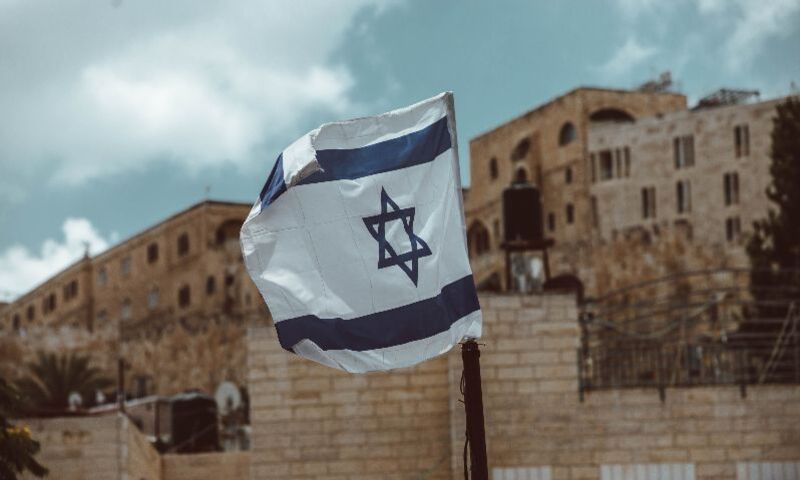 Image shows Israel flag waving amidst city