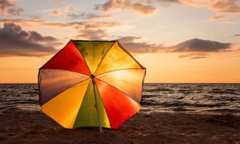Colorful beach umbrella set up with sunset happening behind 