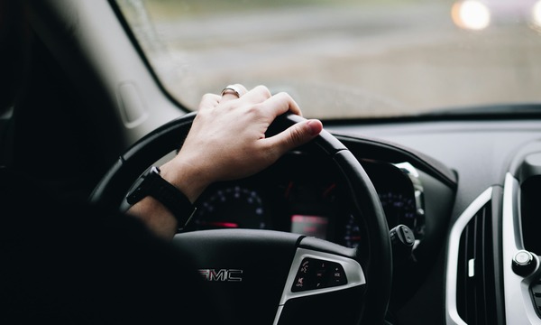 image shows a hand on a steering wheel