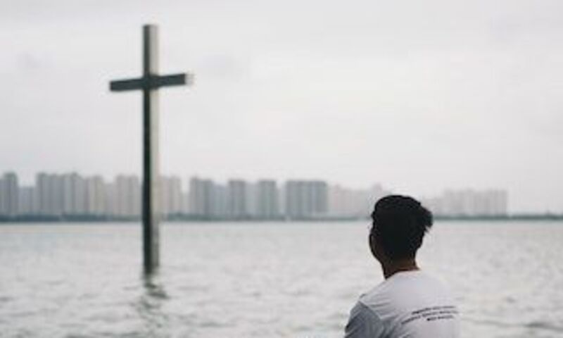 Boy looking at Cross across water