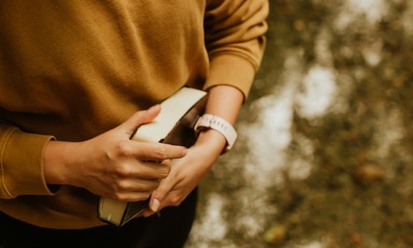 woman in brown long sleeve shirt holding book