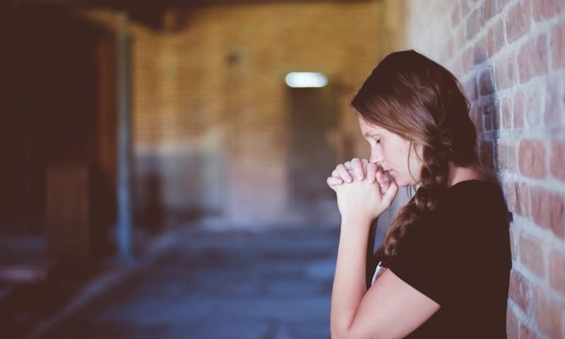 Girl praying against a wall