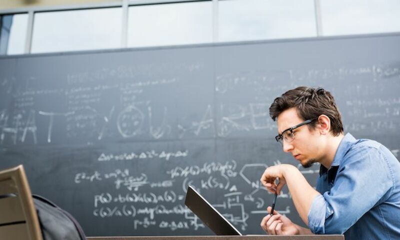 Image shows a computer science student working on his laptop