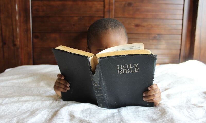 Image shows child reading scripture