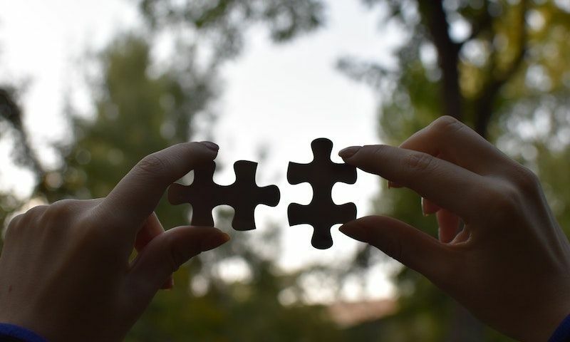 Two hands connecting puzzle pieces