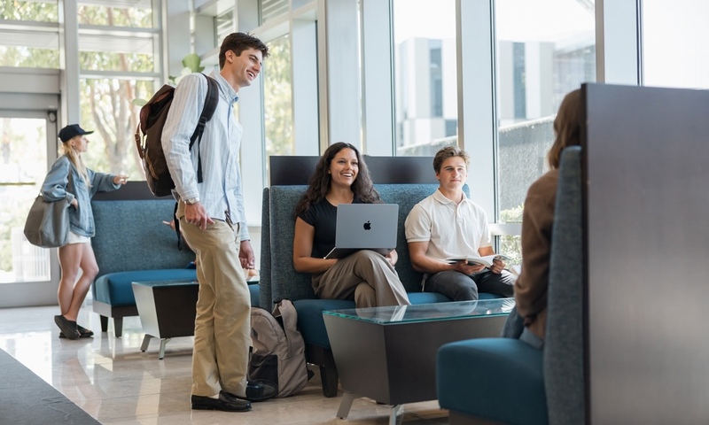 image shows students talking in the Business Building
