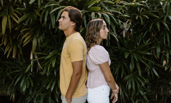 Couple standing back to back with solemn expressions