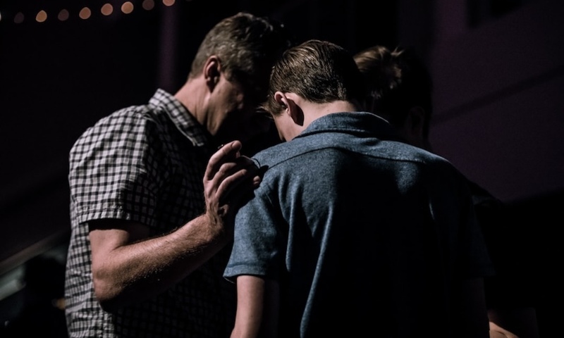 Two men with their heads bowed in prayer