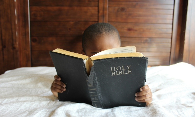 image shows a child reading the Bible 