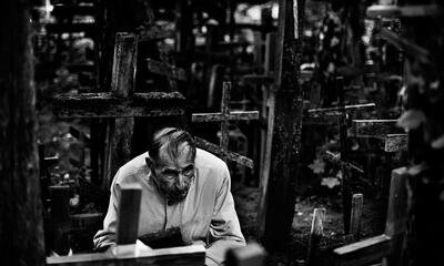 photograph of a man surrounded by wooden crosses