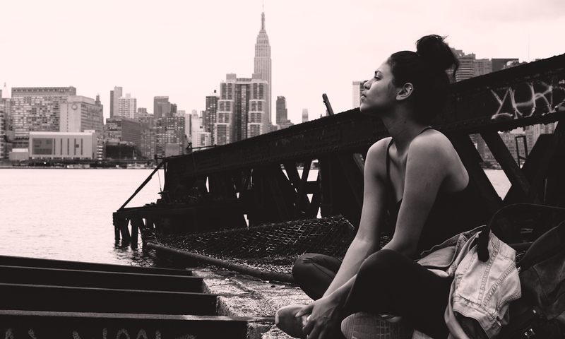 girl sitting down near river bank