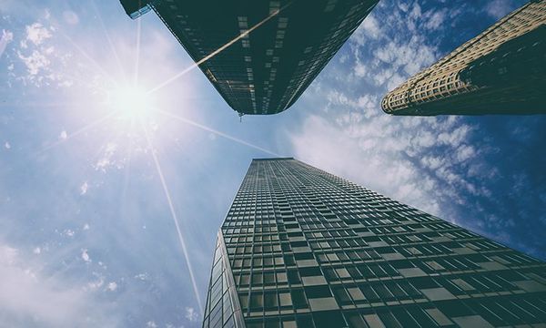 skyscrapers in front of blue sky with clouds and sun