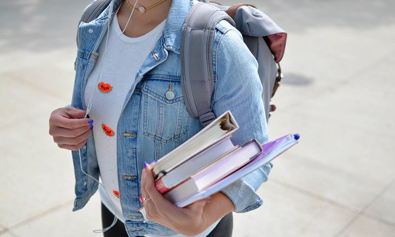 Student carrying a backpack and books