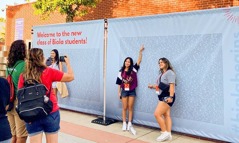 Students point to their names on the new student banners 