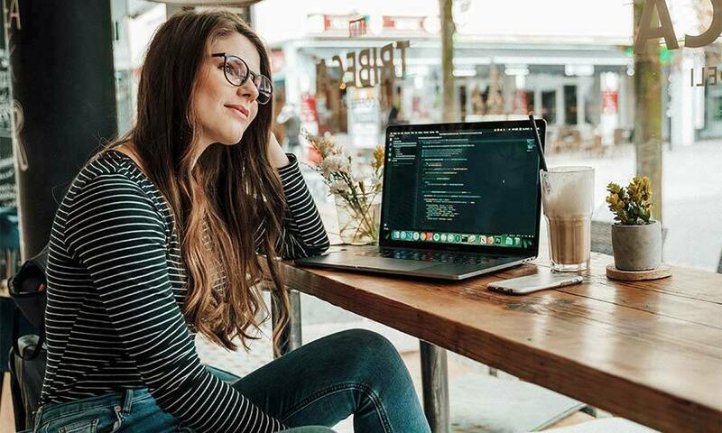 Young woman sitting at a coffee shop with open laptop