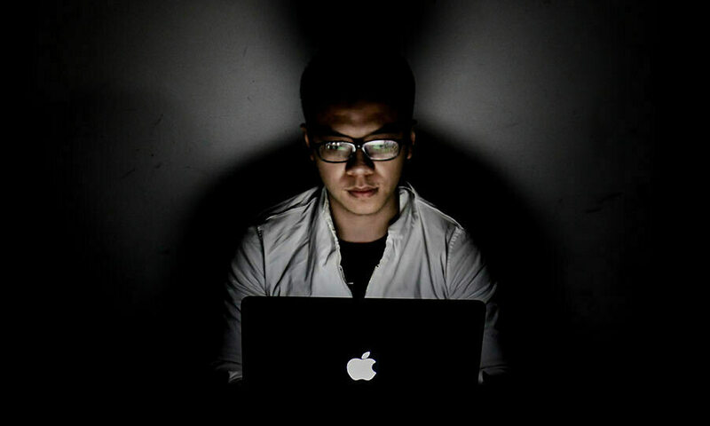 Student working on laptop in dark room