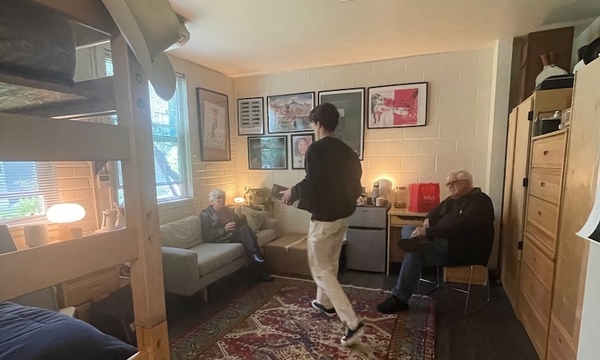 first-year student sits in front of a gallery wall in his dorm room
