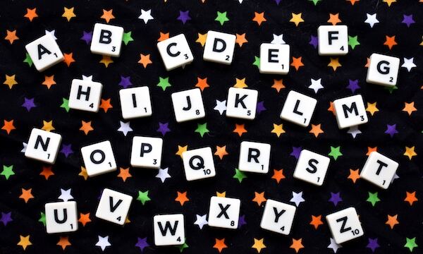 Image shows scrabble alphabet letters on black tablecloth with colored starts printed on fabric