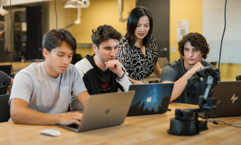 Image shows students working with a professor