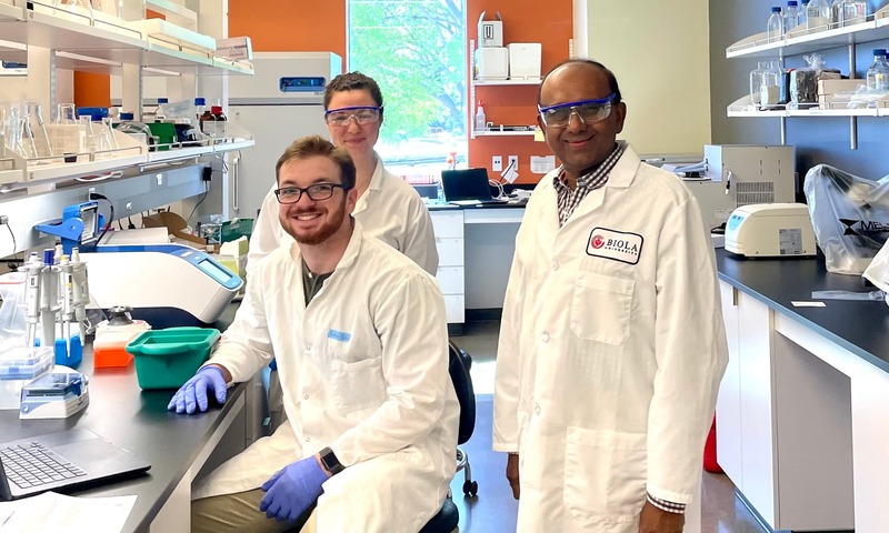 Image shows Gunasekera in the lab with two students