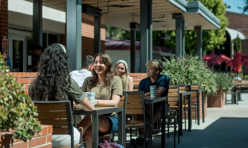 Students sit outside the Commons Cafe and enjoy coffee together 