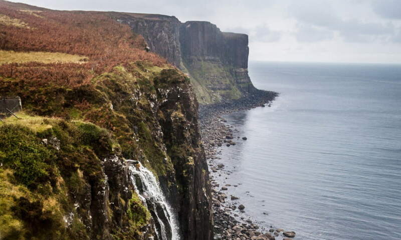 Image shows waterfalls cascading down to ocean off cliffs 