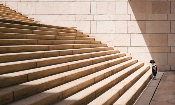 image shows a small child at the foot of a lot of stairs