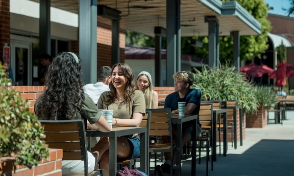 Students sit outside the Commons Cafe and enjoy coffee together 