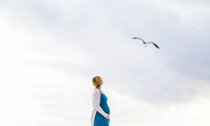 Image shows a pregnant woman looking up at a bird