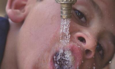 boy drinking from a water spigot