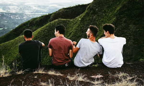 Four men sitting next to each other on top of a mountain