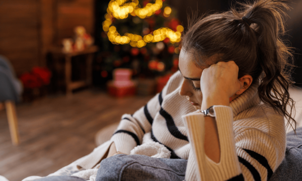 Woman on couch looking sad during Christmas