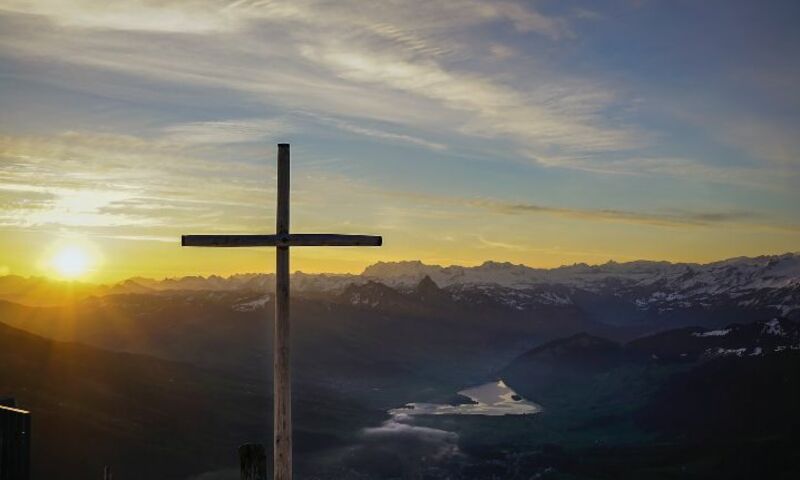 Wooden cross on hill at sunset