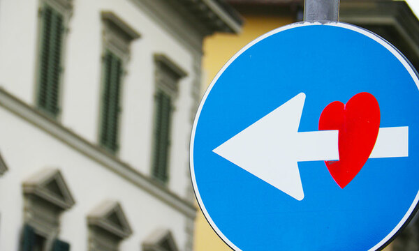 Street sign of arrow pointing through a heart
