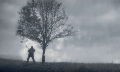 Photograph of a man with an axe and a tree