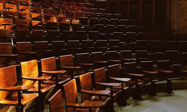 image shows large lecture classroom with wooden seats