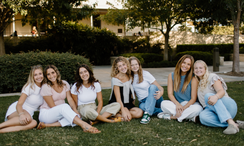 7 girls sitting together on lawn smiling