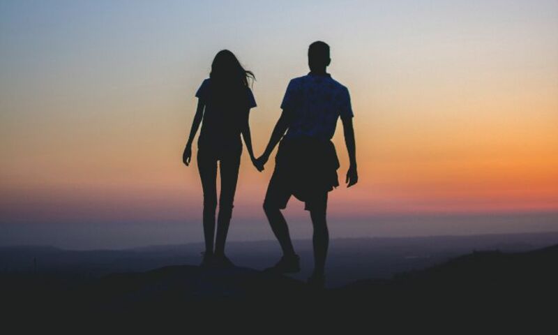 Couple holding hands and looking out over the ocean. 