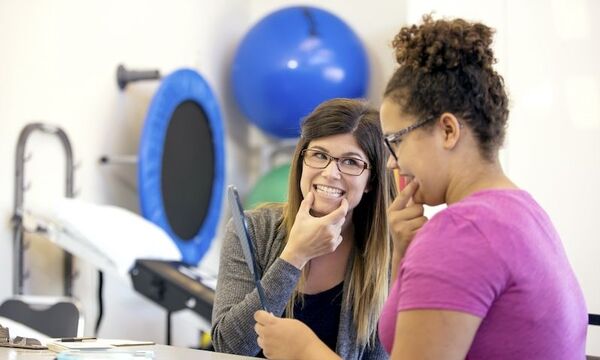 Image shows woman helping with mouth placement for speech therapy