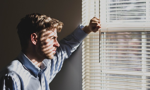 image shows a man looking out a window