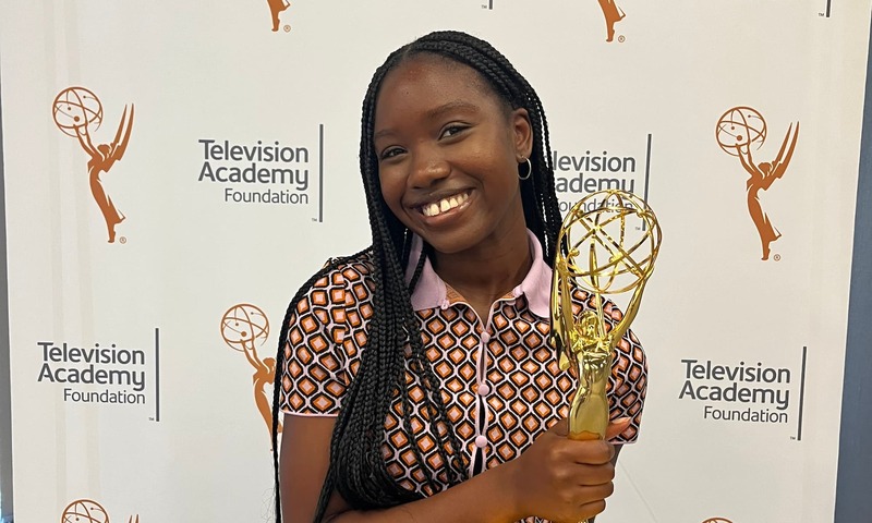 Image shows Dominyk holding an Emmy award