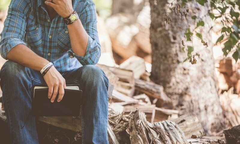 Man thinking in the woods with a book