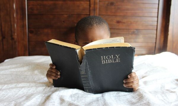 Image shows child reading scripture