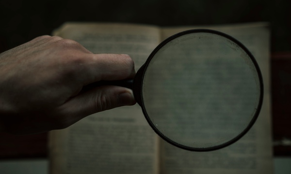image shows a magnifying glass held up to a paper