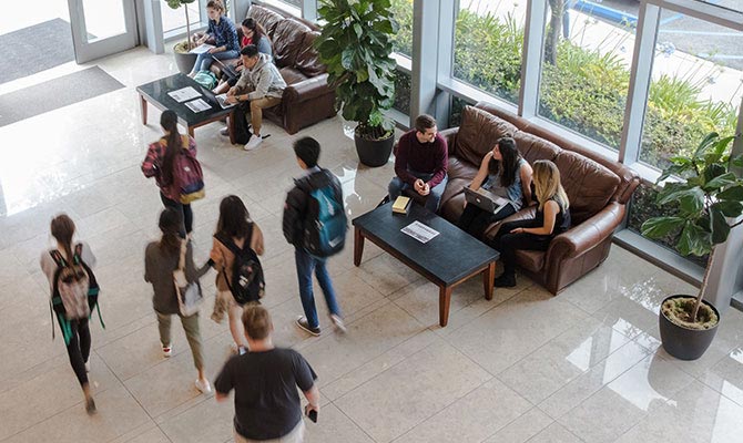 Students walking through and sitting in a lobby