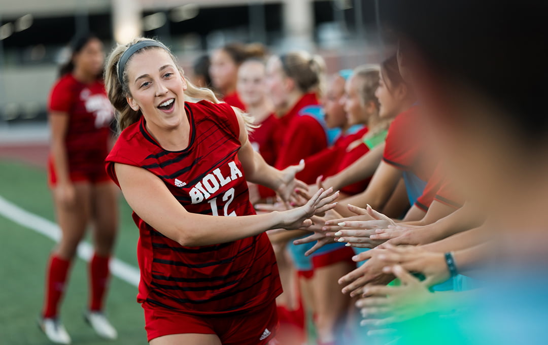 Soccer player giving high fives to her teammates