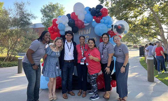 Students smiling in front of balloon arch