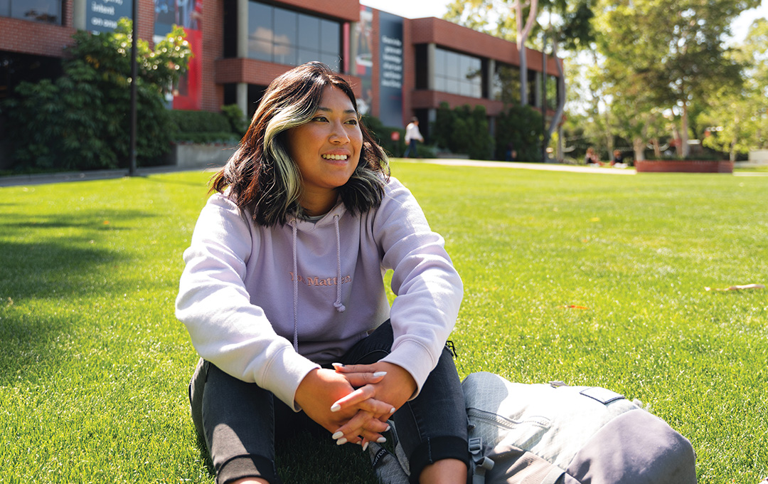 Student sits outside on Metzger Lawn grass