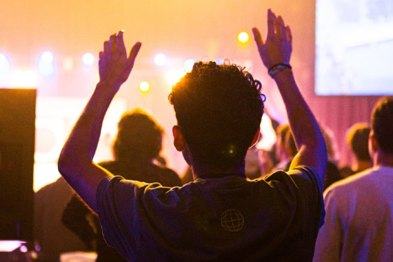 a young man in an audience raising his hands